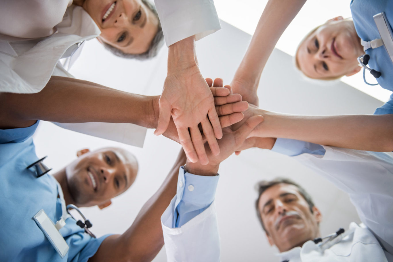 Cheerful doctors and nurses stacking hands in a unified team manner.